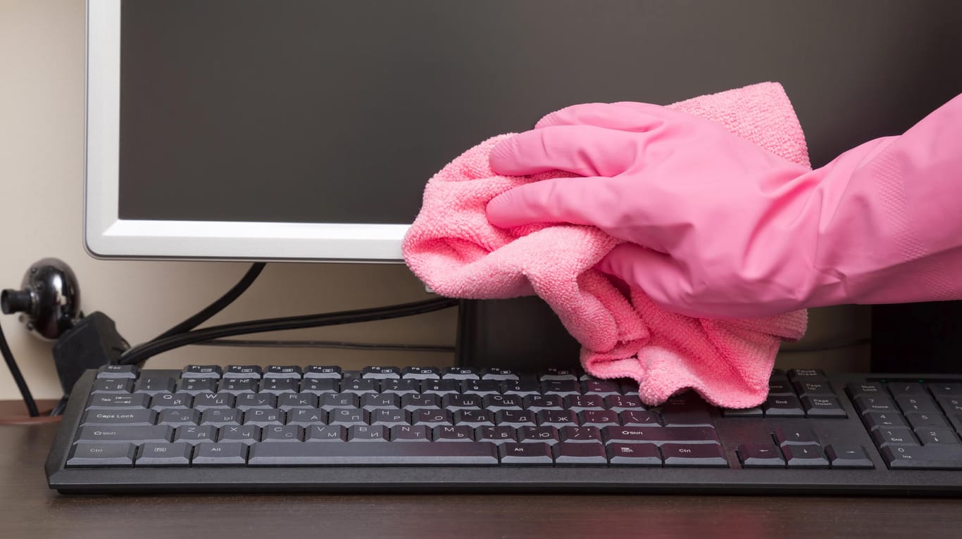 Eine Person reinigt den PC mit Gummihandschuh und Staubtuch: Bei der Wahl der Putzmittel müssen Nutzer vorsichtig sein.