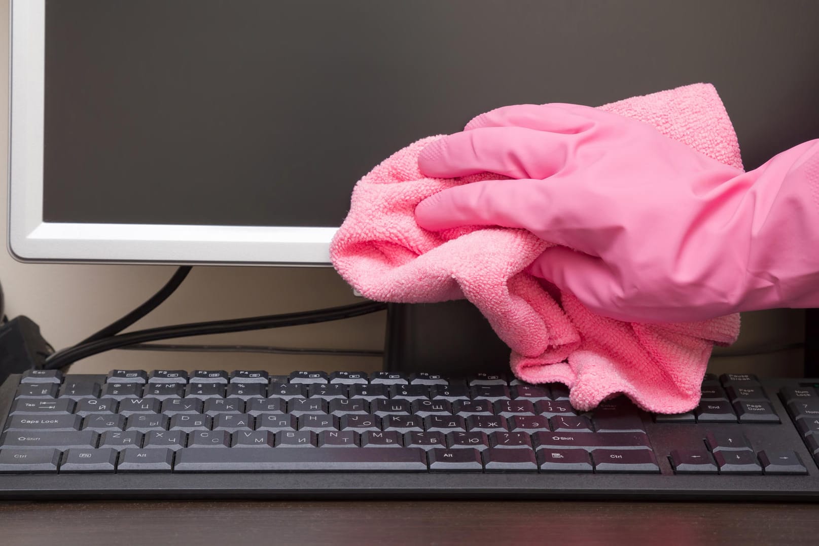 Eine Person reinigt den PC mit Gummihandschuh und Staubtuch: Bei der Wahl der Putzmittel müssen Nutzer vorsichtig sein.