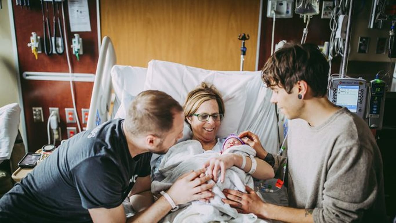 Matthew Eledge (l), seine Mutter Cecile Eledge und Matthews Mann, Elliot Dougherty, heißen Baby Uma nach ihrer Geburt willkommen.