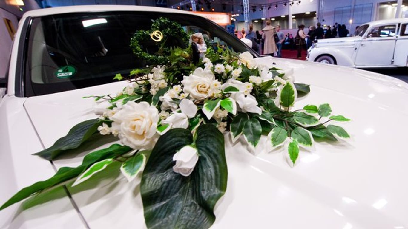Schöne Blumen auf der Motorhaube sind ein typischer Schmuck fürs Hochzeitsauto - sie dürfen dem Fahrer aber nicht die Sicht nehmen.