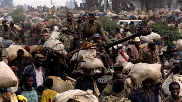Rwandan government soldiers atop a tank equipped with a 90mm gun flee civilians in front of advancin..