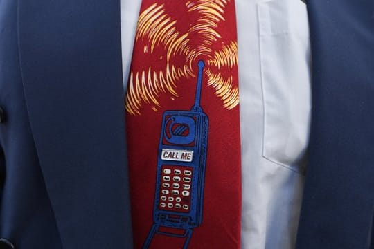 Ein Bieter trägt beim Start der Auktion von 5G-Mobilfunkfrequenzblöcken am Mainzer Technik-Standort der Bundesnetzagentur eine Krawatte mit einem Mobiltelefon.