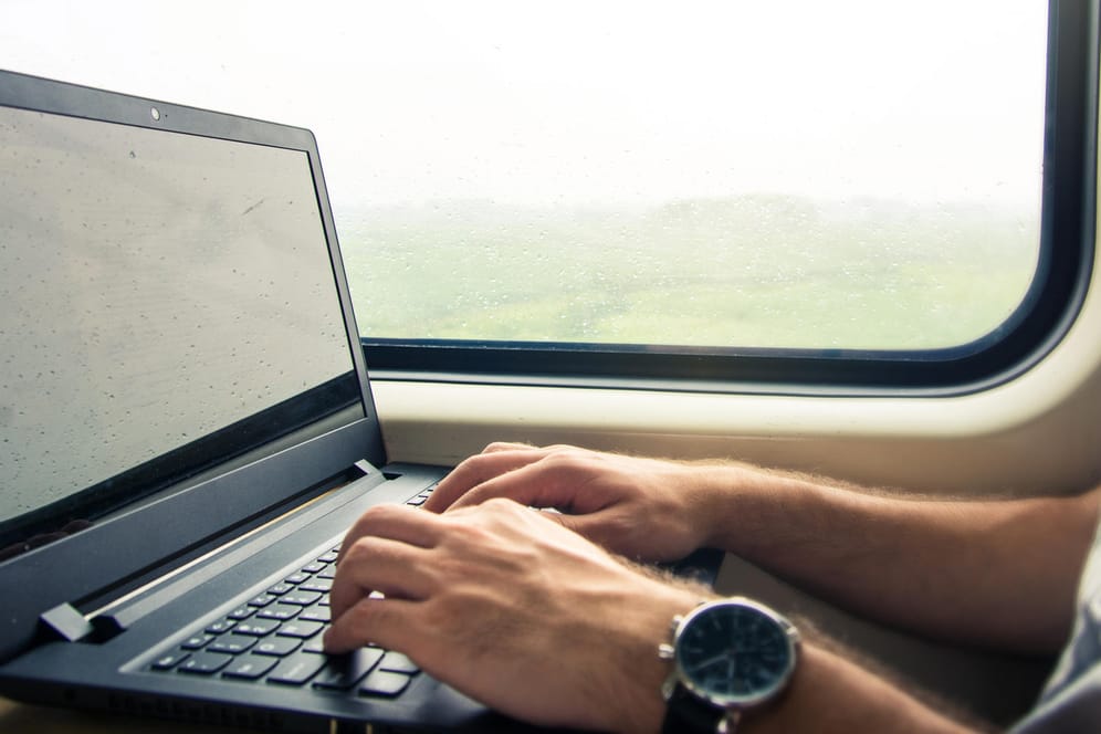Ein Mann im Zug arbeitet an einem Laptop: Windows 10 bietet viele Möglichkeiten, das System nach eigenen Bedürfnisse zu optimieren.