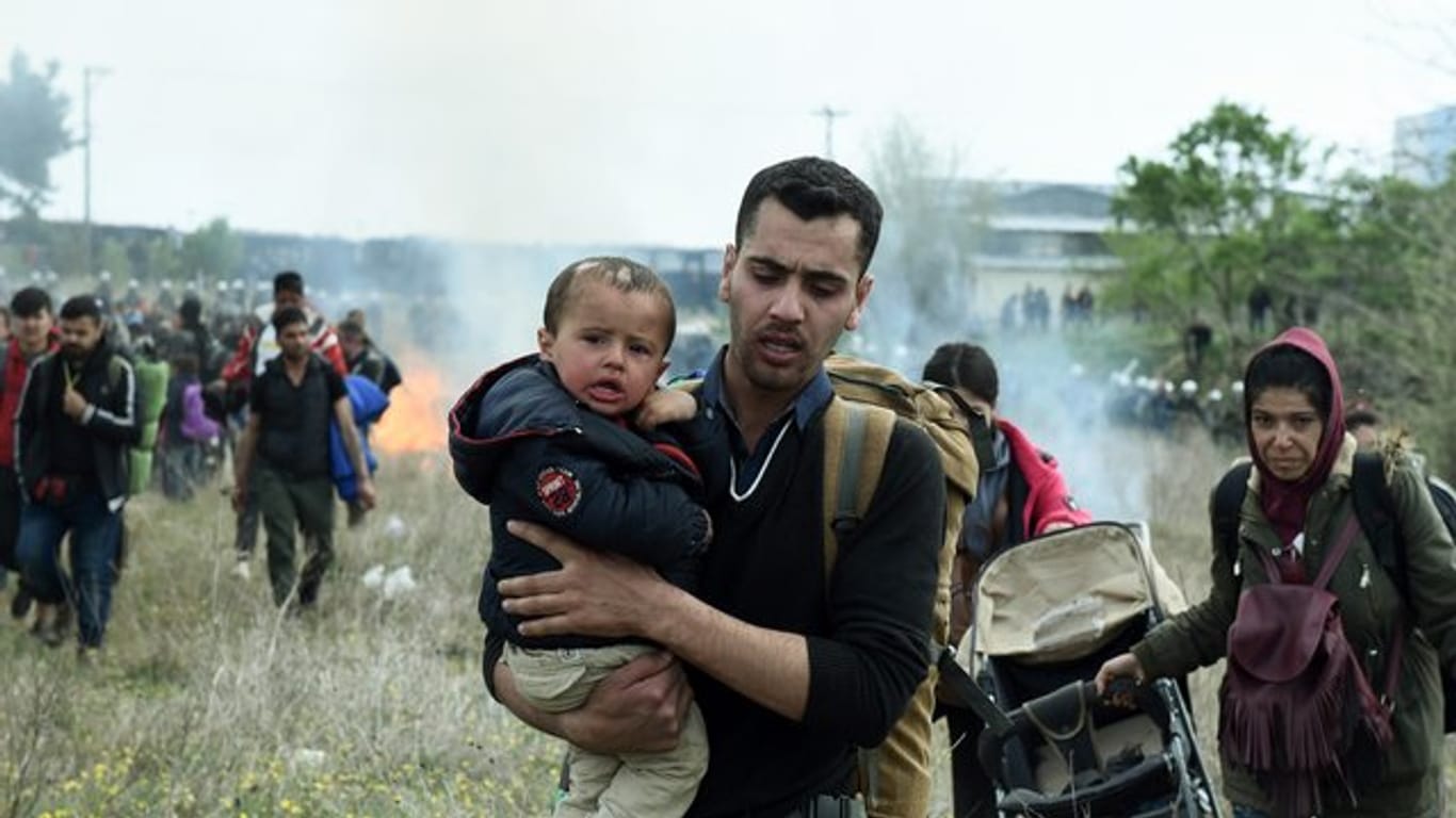 Ein Mann hält ein Baby auf dem Arm, während die Bereitschaftspolizei Tränengas einsetzt.