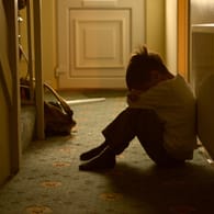 Ein Junge sitzt im Flur: Sexueller Kindesmissbrauch hat für die Opfer meist lebenslange Folgen.
