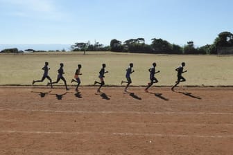 Eine Gruppe kenianischer Läufer zieht auf der Sandbahn des Sportplatzes in Iten ihre Runden.