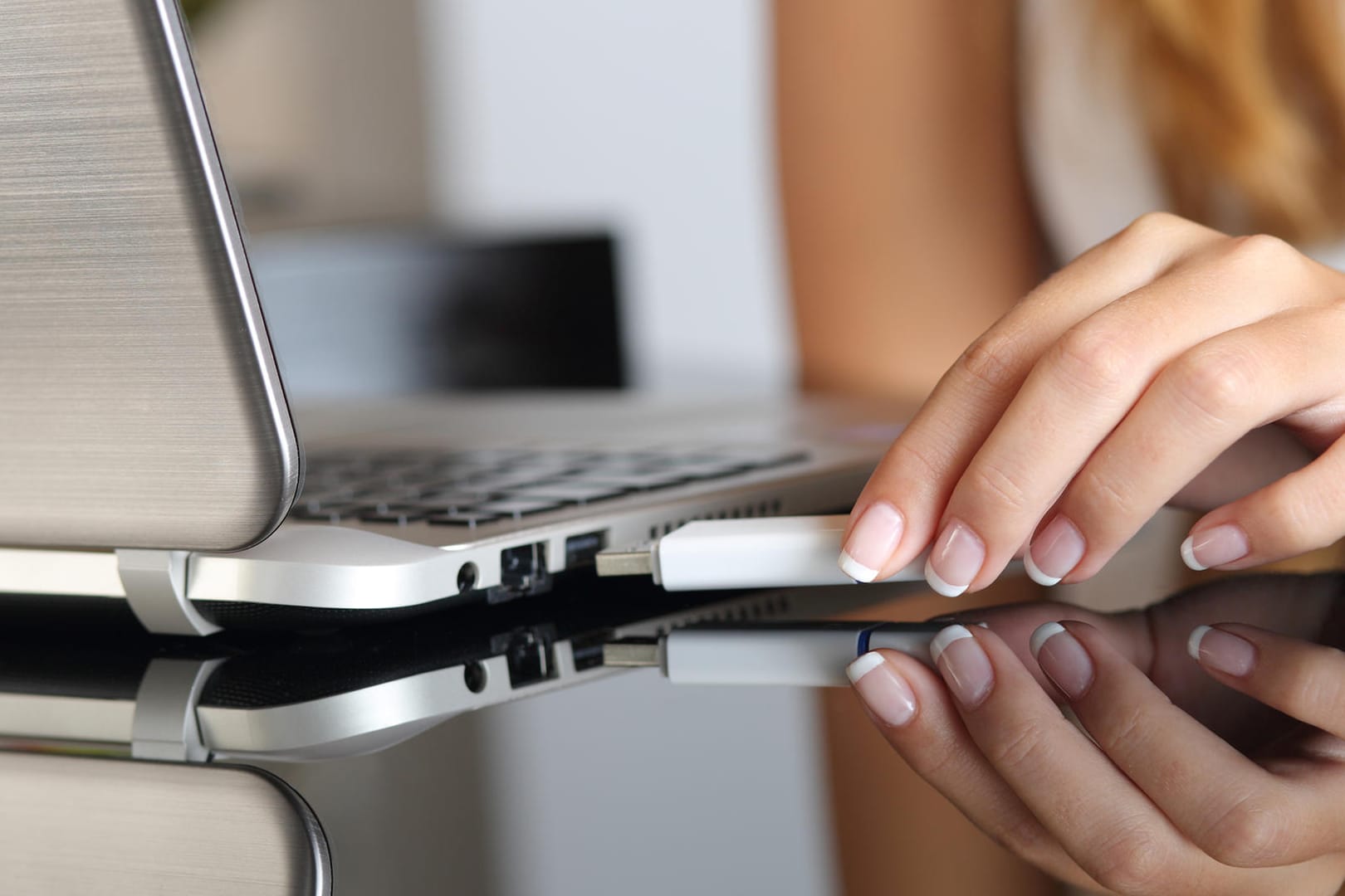 Eine Frau steckt einen USB-Stick in einen Laptop: Nach dem neuen Windows-Update müssen Nutzer externe Datenträger nicht mehr "sicher entfernen".