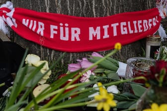 Berlin: Blumen und Kerzen sowie ein Fan-Schal vom FC Union haben Menschen auf einem Parkplatz an der Stahlheimer Straße abgelegt.