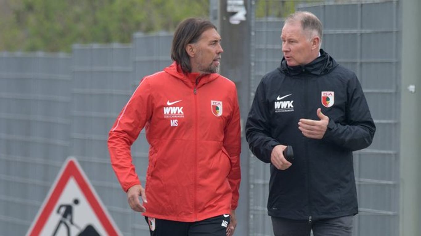 An seinem ersten Arbeitstag geht Augsburgs neuer Trainer Martin Schmidt (l) mit Sportdirektor Stefan Reuter zum Übungsgelände.