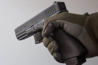 Eine Hand hält eine Pistole: Der Mann hatte sich zuvor in dem Geschäft nach Vogelfutter erkundigt, anschließend kam er mit einer Waffe zurück. (Symbolbild)