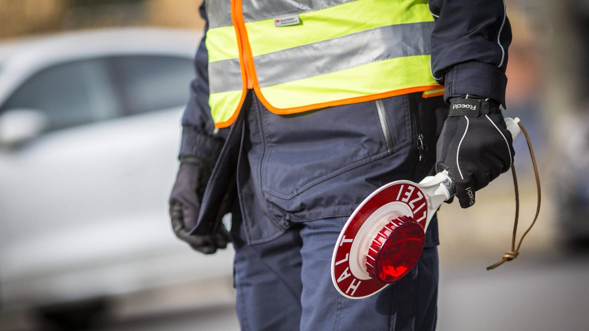 Ein Polizeibeamter mit Polizeikelle: Ein Mann ist nach einer Verkehrskontrolle im Krankenhaus verstorben. (Symbolbild)