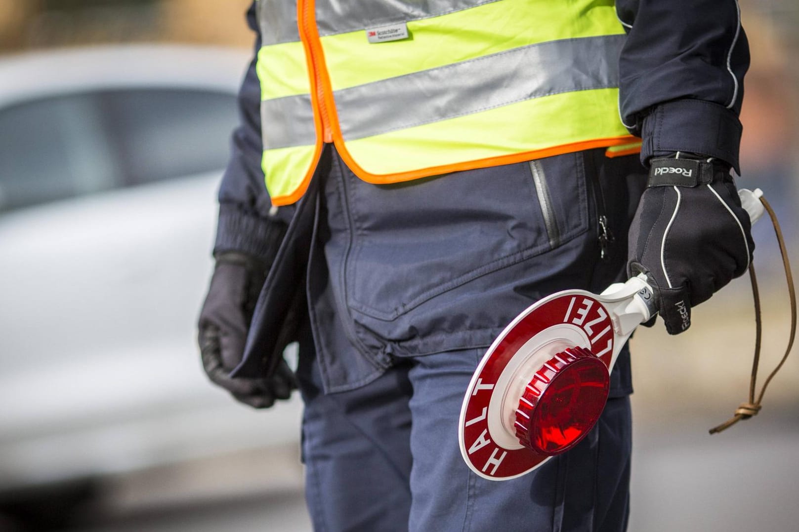 Ein Polizeibeamter mit Polizeikelle: Ein Mann ist nach einer Verkehrskontrolle im Krankenhaus verstorben. (Symbolbild)