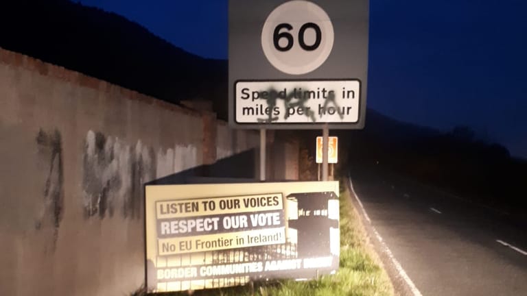 Ein Schild an der Grenze zwischen Irland und Nordirland: Alles, was auf die Trennlinie hinweist, ist ein Schild, das Autofahrer darauf aufmerksam macht, dass Geschwindigkeitsangaben in Nordirland als Teil Großbritanniens in Meilen pro Stunde erfolgen. Das IRA-Graffiti erinnert an dunkle Zeiten. Aufgenommen nahe Newry.