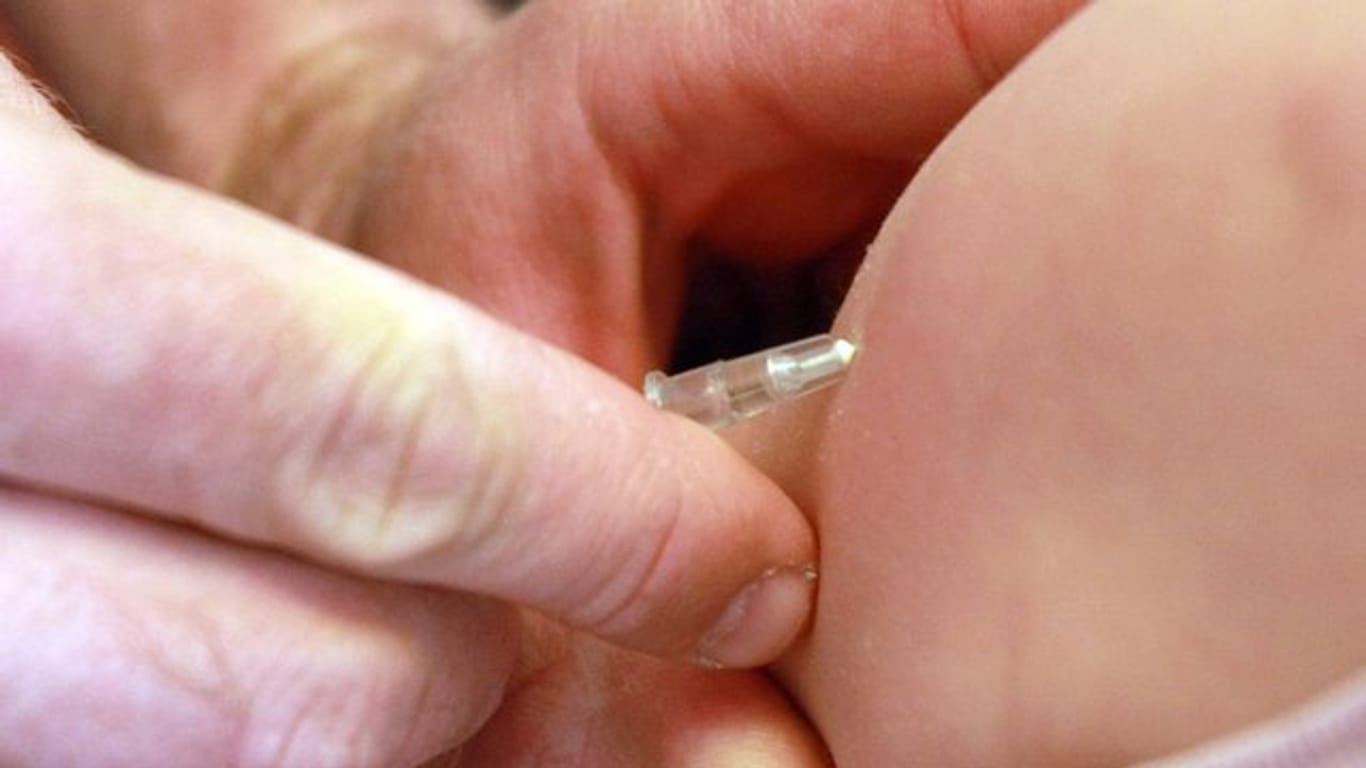 Ein Kinderarzt impft ein Mädchen gegen Masern.