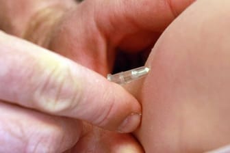 Ein Kinderarzt impft ein Mädchen gegen Masern.