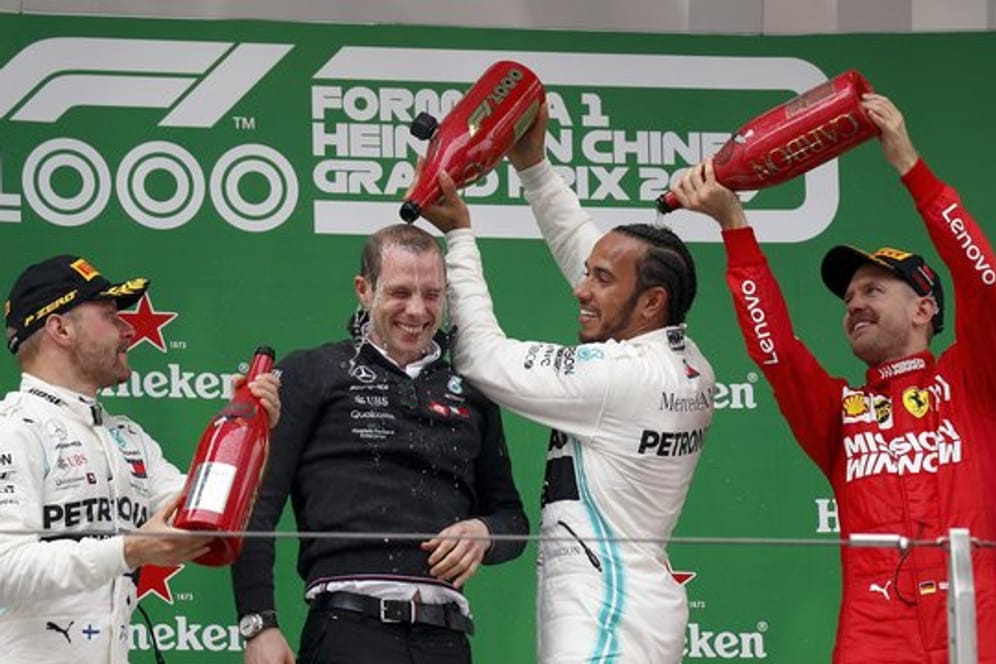 Sebastian Vettel (r) spendiert für Sieger Lewis Hamilton eine Champagner-Dusche.