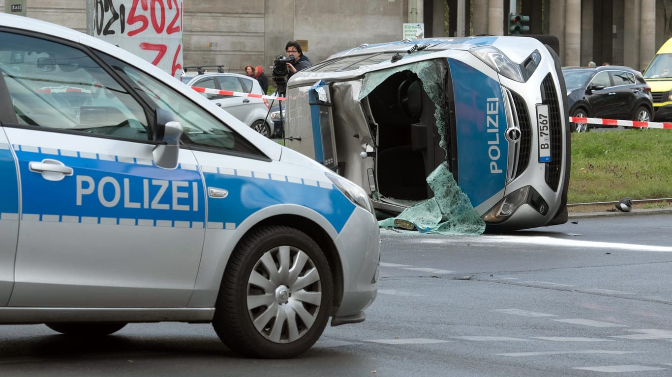 Berlin: Ein umgekippter Streifenwagen liegt nach einem Zusammenstoß mit einem Pkw auf einem Grünstreifen am Frankfurter Tor.