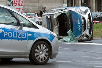 Berlin: Ein umgekippter Streifenwagen liegt nach einem Zusammenstoß mit einem Pkw auf einem Grünstreifen am Frankfurter Tor.