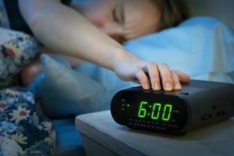 Frau betätigt Schlummerfunktion: Ob jemand morgens snoozt oder nicht, dürfte auch mit dem Geschlecht zusammenhängen.
