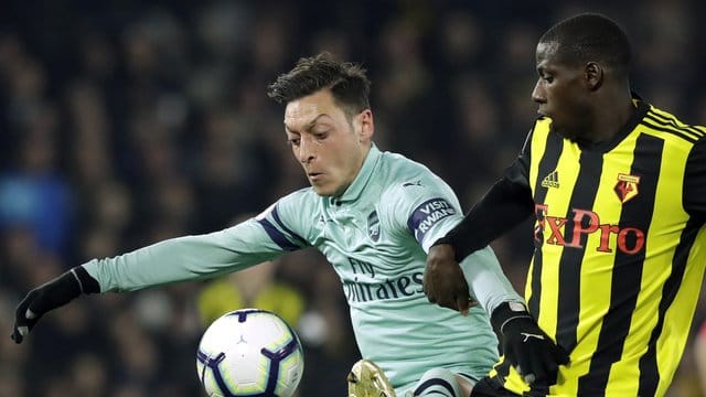 Arsenal-Spieler Mesut Özil (l) behauptet sich gegen Abdoulaye Doucoure vom FC Watford beim Kampf um den Ball. Arsenal-Spieler Mesut Özil (l) behauptet sich gegen Abdoulaye Doucoure vom FC Watford beim Kampf um den Ball.