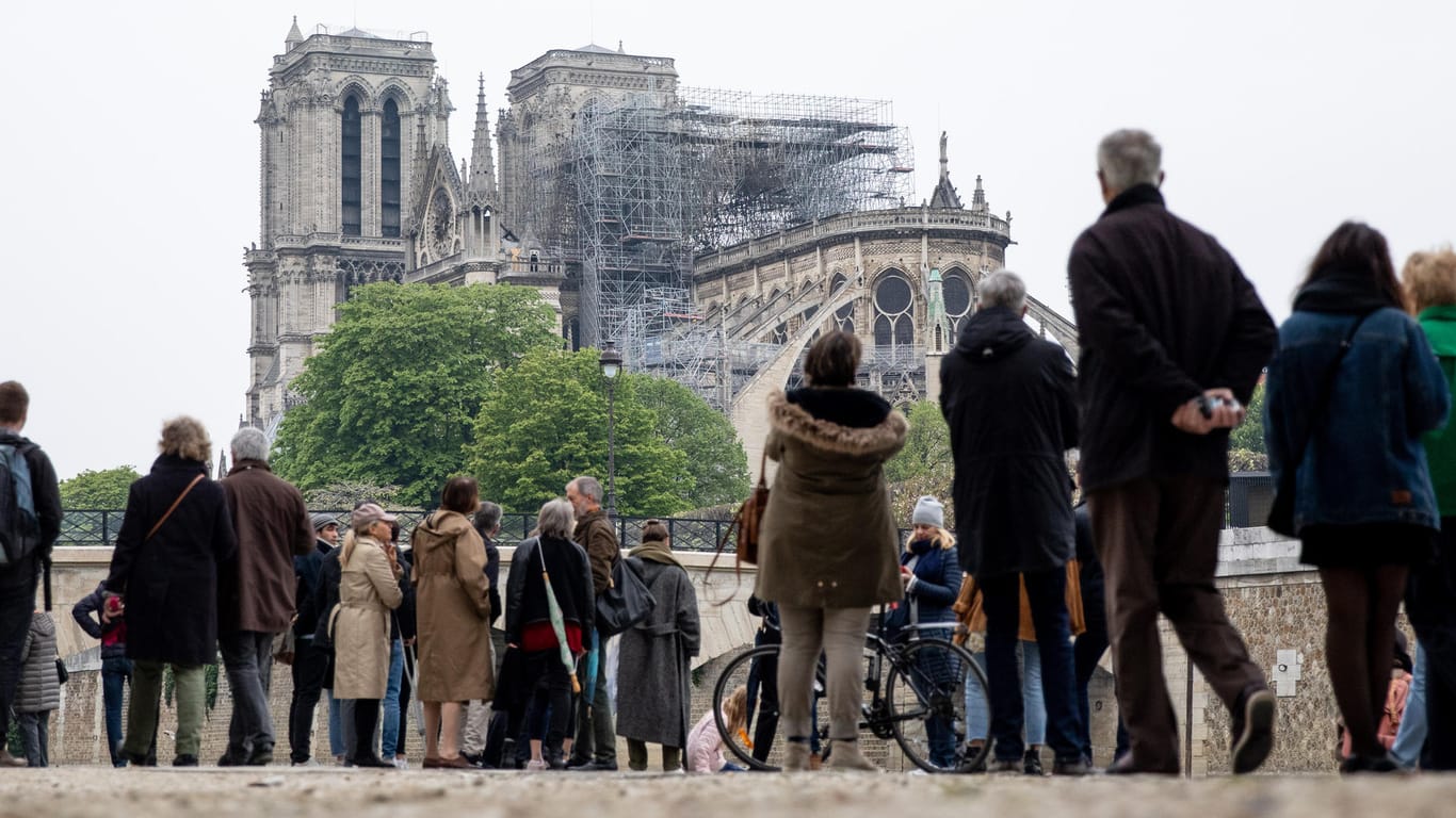Zahlreiche Menschen schauen zur Kathedrale Notre-Dame: Der Wiederaufbau der Kathedrale wird Millionen kosten.