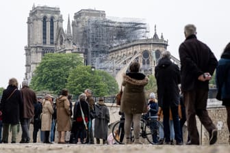 Zahlreiche Menschen schauen zur Kathedrale Notre-Dame: Der Wiederaufbau der Kathedrale wird Millionen kosten.