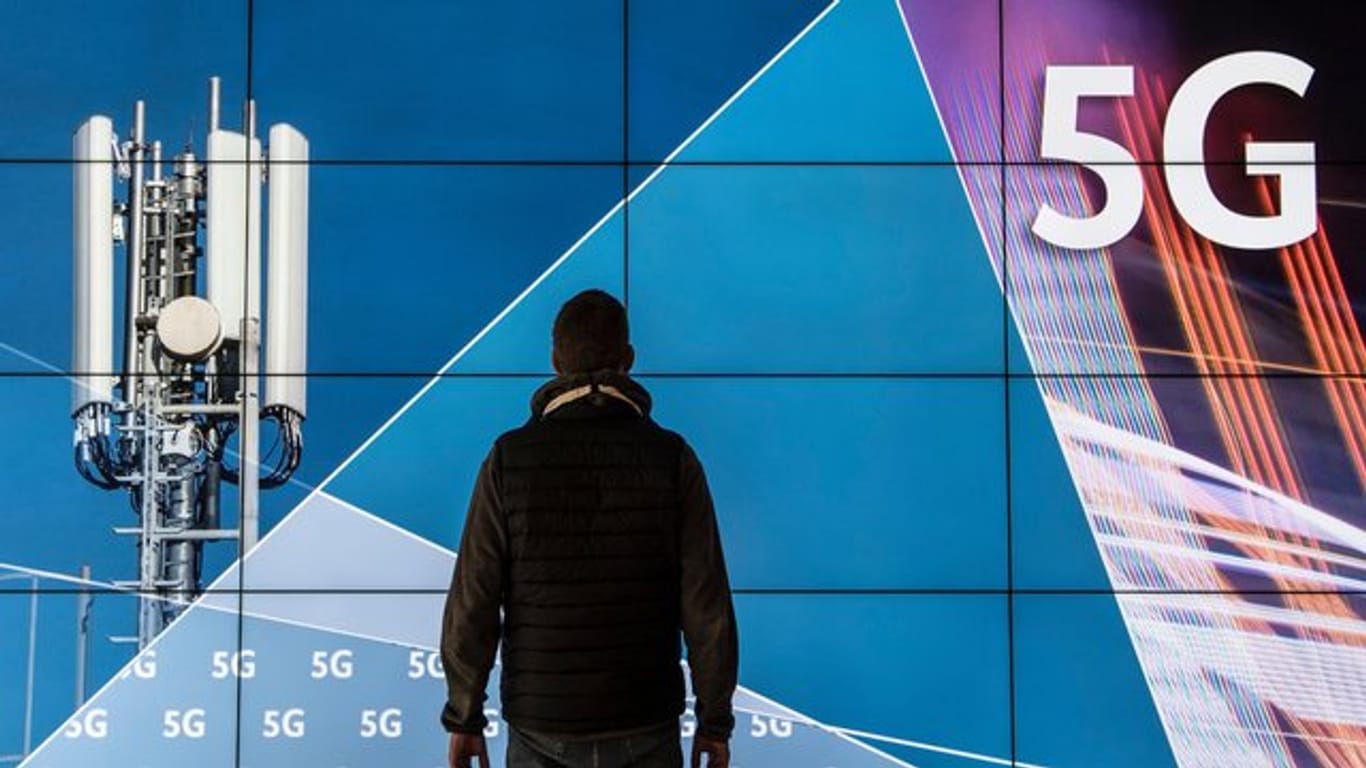 Ein Mann steht im Gebäude der Bundesnetzagentur vor einer Leinwand mit der Aufschrift "5G".