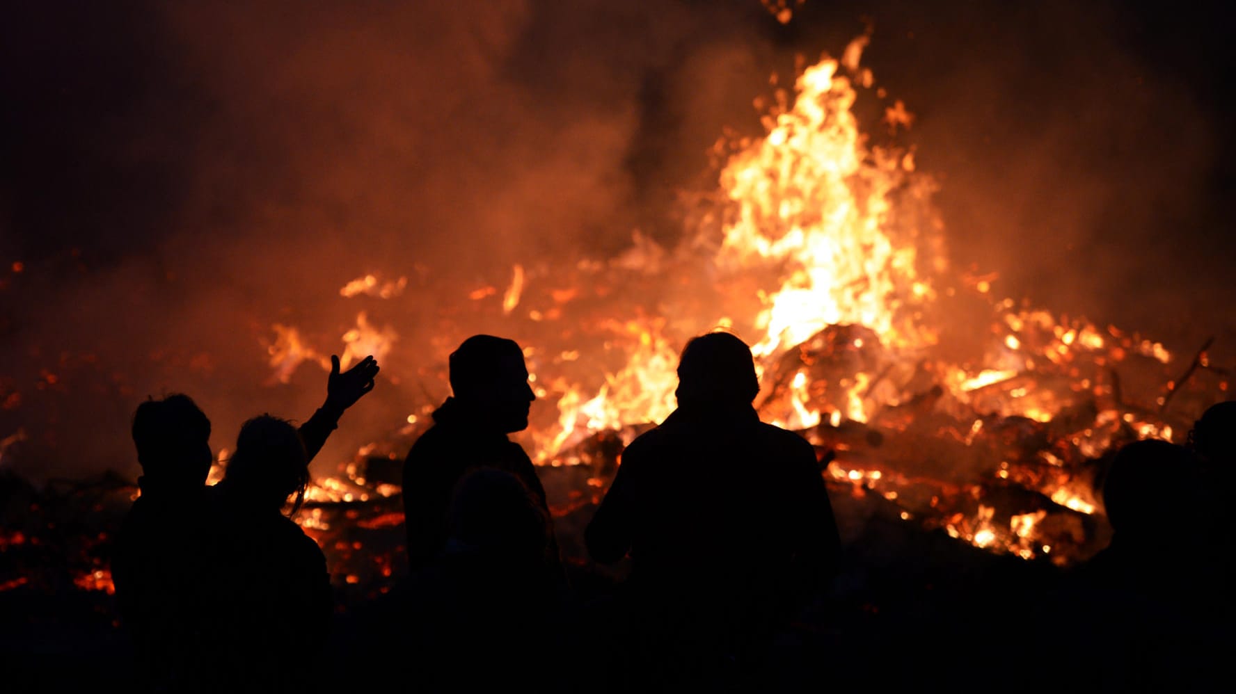 Menschen stehen an einem Osterfeuer: Angesichts der hohen Waldbrandgefahr hat der Beauftragte des Landes Brandenburg zu besonderer Vorsicht bei den traditionellen Osterfeuern gemahnt.