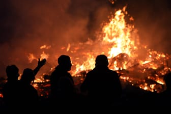Menschen stehen an einem Osterfeuer: Angesichts der hohen Waldbrandgefahr hat der Beauftragte des Landes Brandenburg zu besonderer Vorsicht bei den traditionellen Osterfeuern gemahnt.