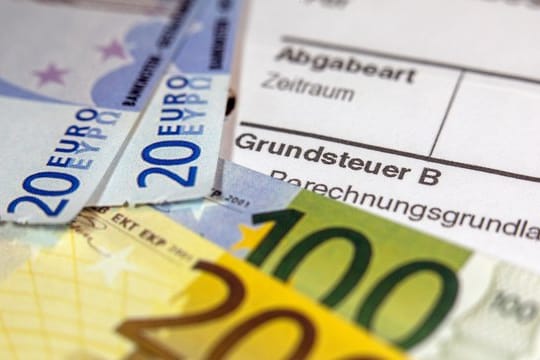 Euro-Geldscheinen liegen auf einem Abgabenbescheid für die Entrichtung der Grundsteuer.