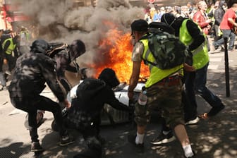 Teilnehmer der Demonstration stehen vor einem brennenden Motorrad: Am 20.04.2019 fanden erneut «Gelbwesten»-Demonstrationen in Paris statt.