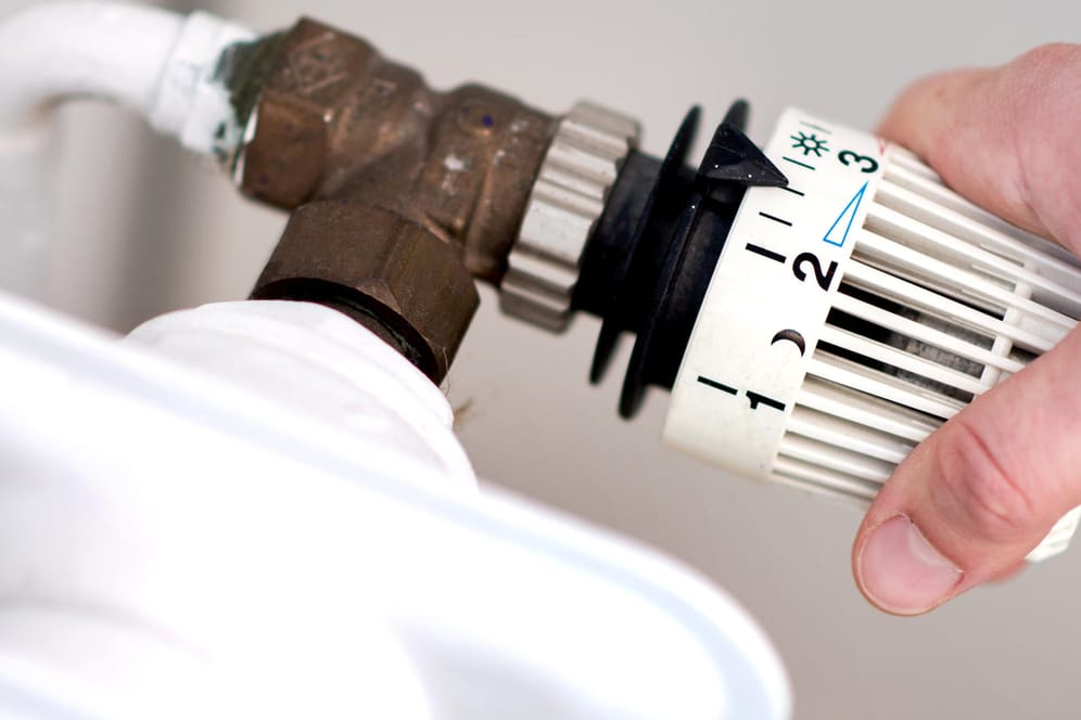 Eine Frau dreht am Thermostat einer Heizung: Anders als Haushalte mit Ölheizung, profitieren die mit Gasheizung vom milden Winter.