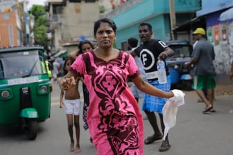 Eine Straße in Colombo: Eine srilankanische Frau, die in der Nähe des St-Antonius-Kirche wohnt, läuft in Sicherheit. Am Ostermontag fand die Polizei weitere Sprengsätze in einem in der Nähe der Kirche geparkten Fahrzeug.