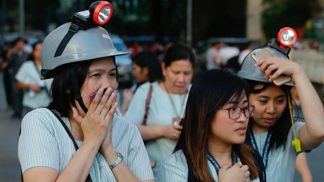Philippinen, Manila: Nach einem Erdbeben verlassen Mitarbeiter mit Schultzhelmen ihre Büros.