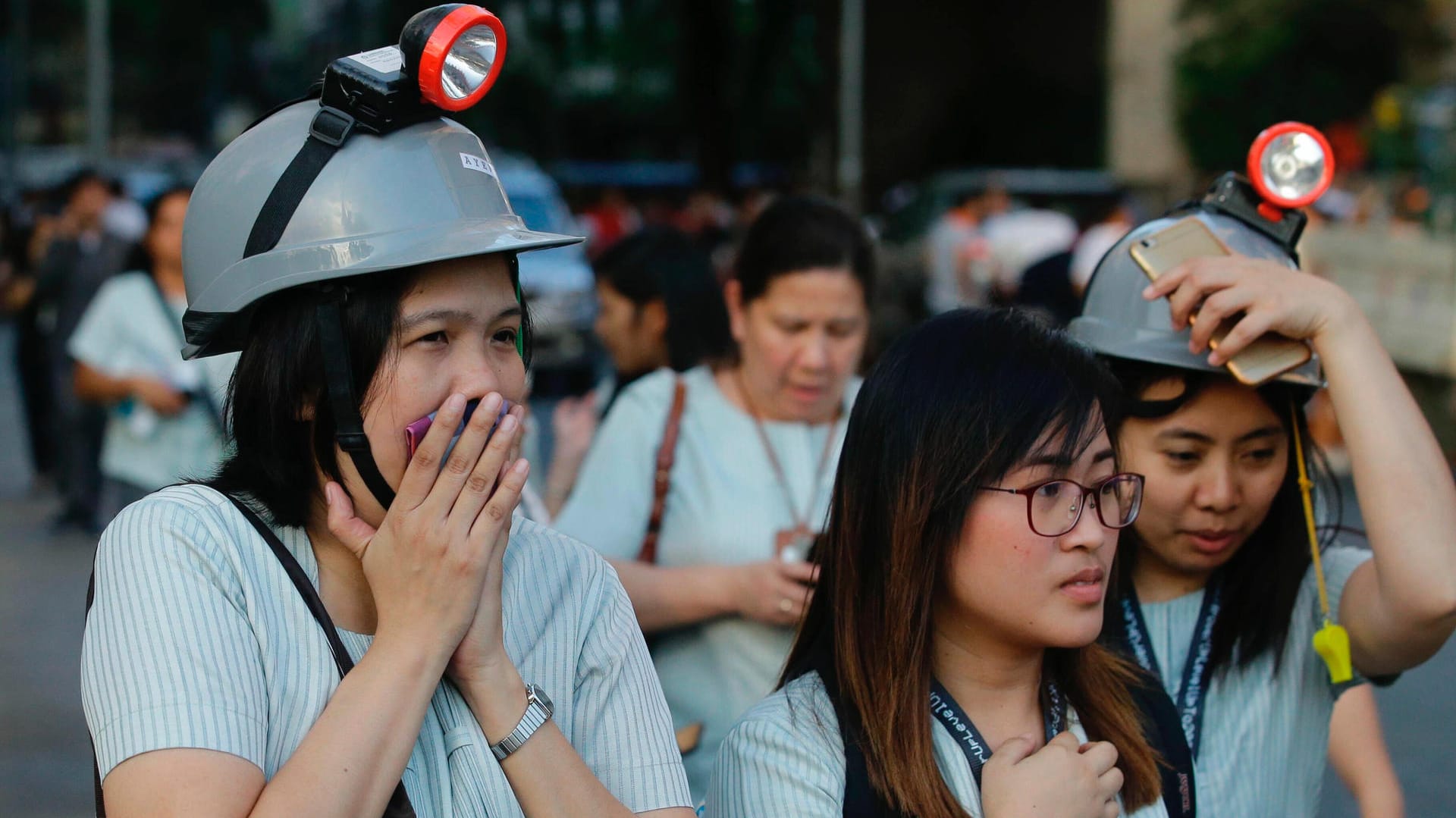 Philippinen, Manila: Nach einem Erdbeben verlassen Mitarbeiter mit Schultzhelmen ihre Büros. Philippinen, Manila: Nach einem Erdbeben verlassen Mitarbeiter mit Schultzhelmen ihre Büros.