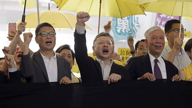 Die Anführer der "Regenschirm-Bewegung", Chan Kin Man (l-r), Benny Tai und Chu Yiu Ming rufen Parolen, bevor sie ins Gericht gehen. Die Anführer der "Regenschirm-Bewegung", Chan Kin Man (l-r), Benny Tai und Chu Yiu Ming rufen Parolen, bevor sie ins Gericht gehen.