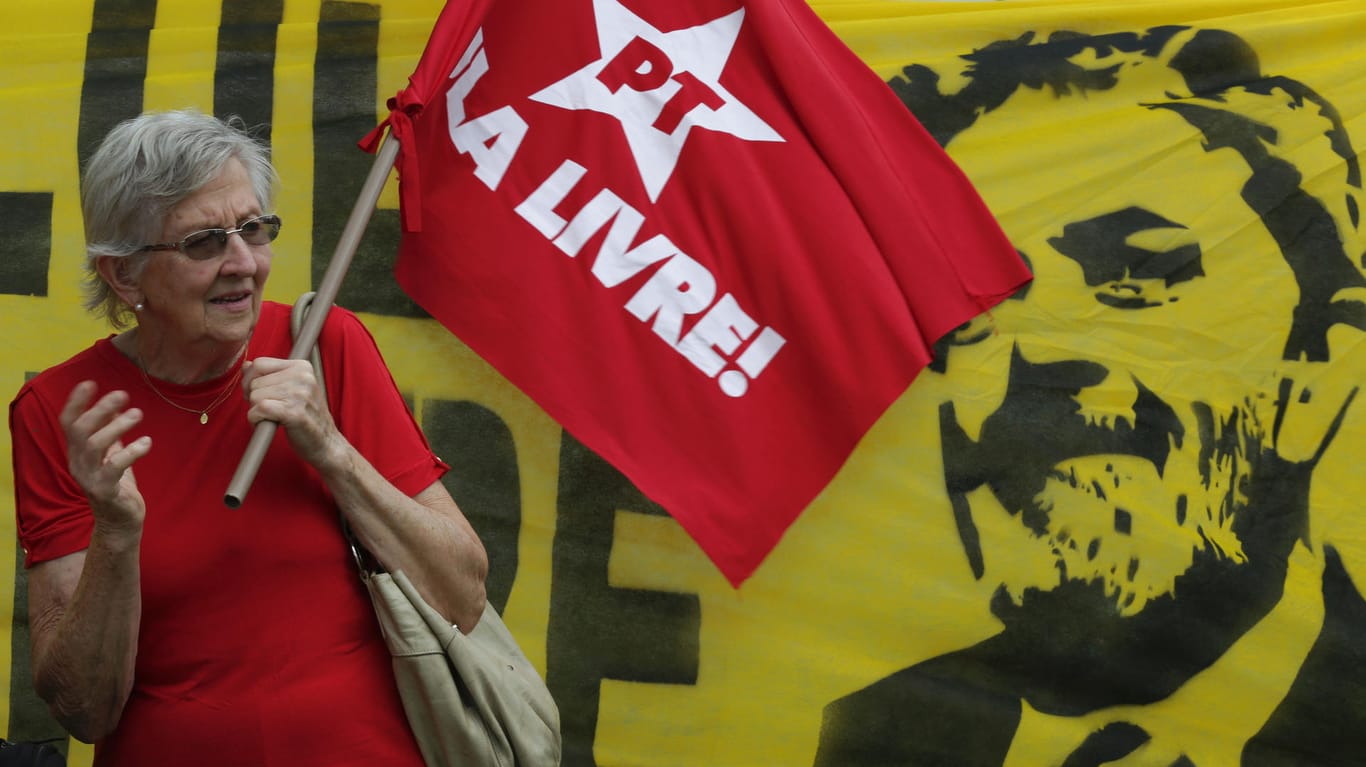 Eine Frau hält eine Flagge der Arbeiterpartei vor einem Plakat des Ex-Präsidenten
