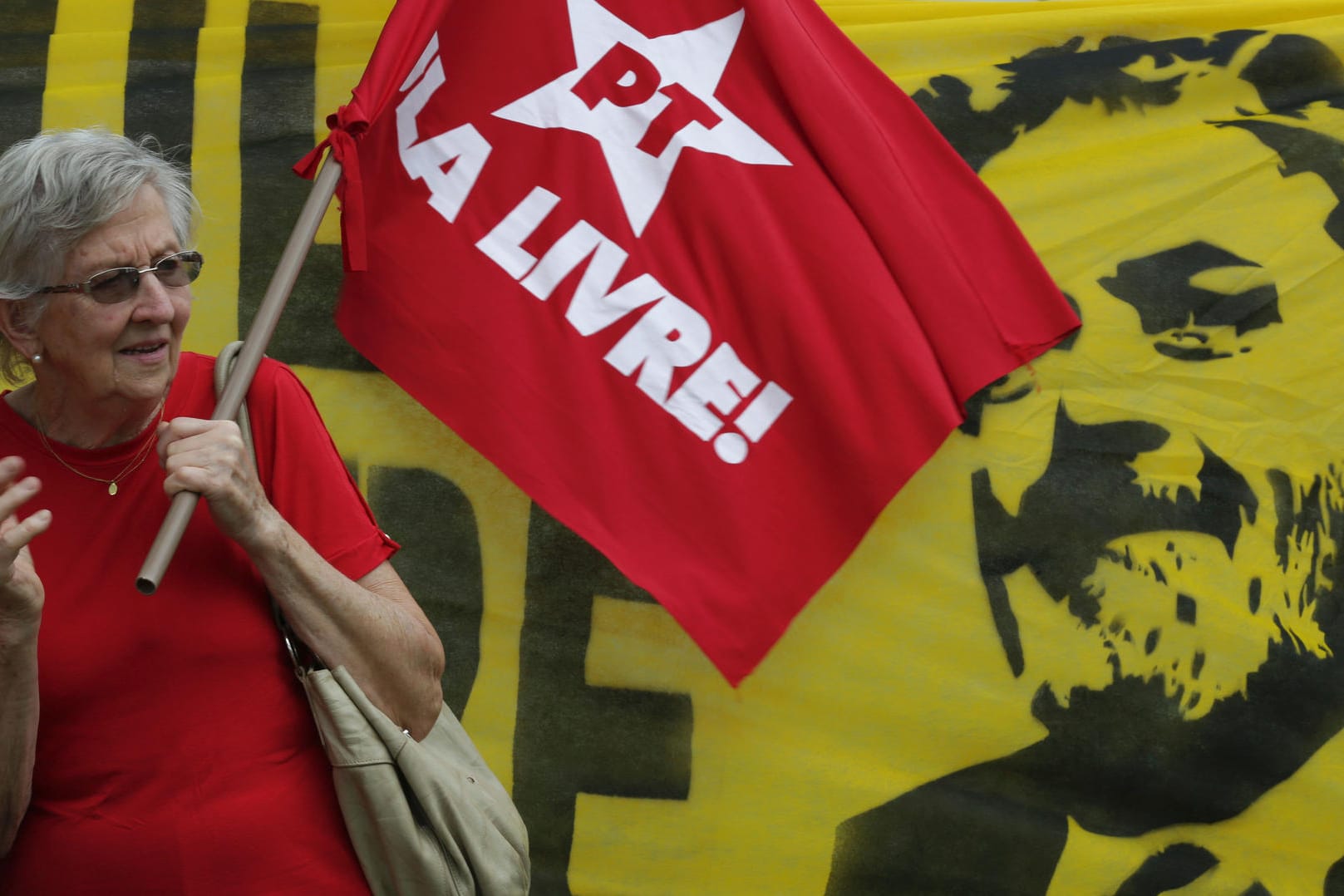 Eine Frau hält eine Flagge der Arbeiterpartei vor einem Plakat des Ex-Präsidenten
