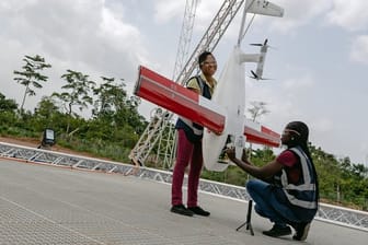 Mitarbeiterinnen des Unternehmens Zipline bereiten eine Drohne für einen Start mit Impfstoffen und anderen Medikamenten vor.