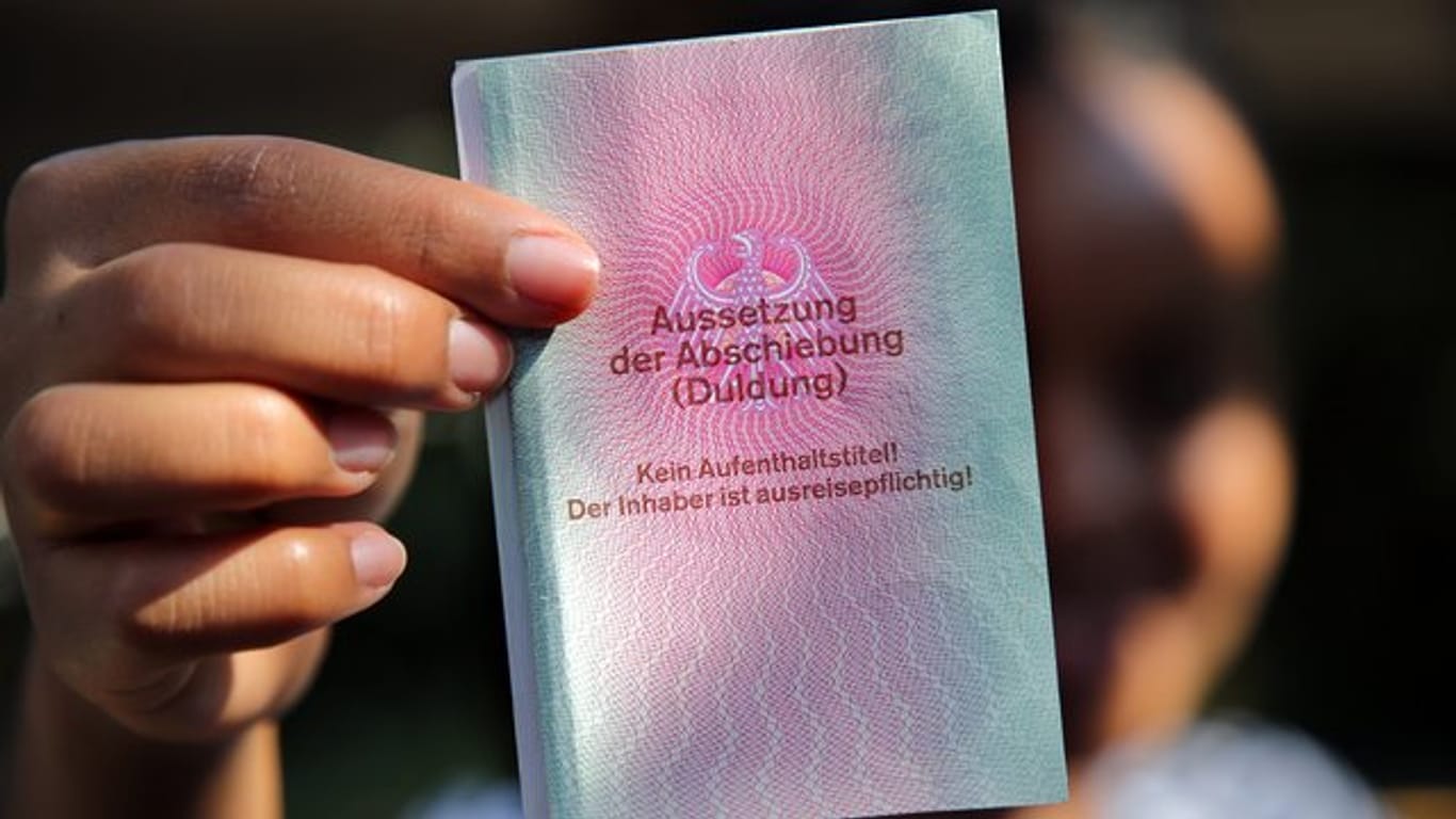 Eine junge Frau hält einen Ausweis für Flüchtlinge in der Hand mit dem Titel: Aussetzung der Abschiebung (Duldung).
