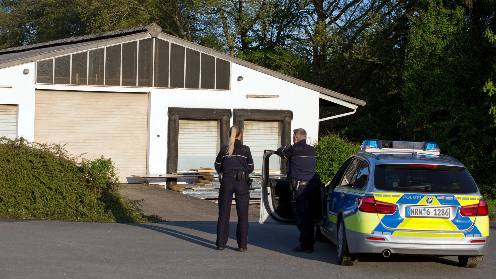 Polizeibeamte stehen vor der Lagerhalle: Unter anderem lagerten Schwefelsäure, Natronlauge und Phosphorsäure in dem Gebäude.