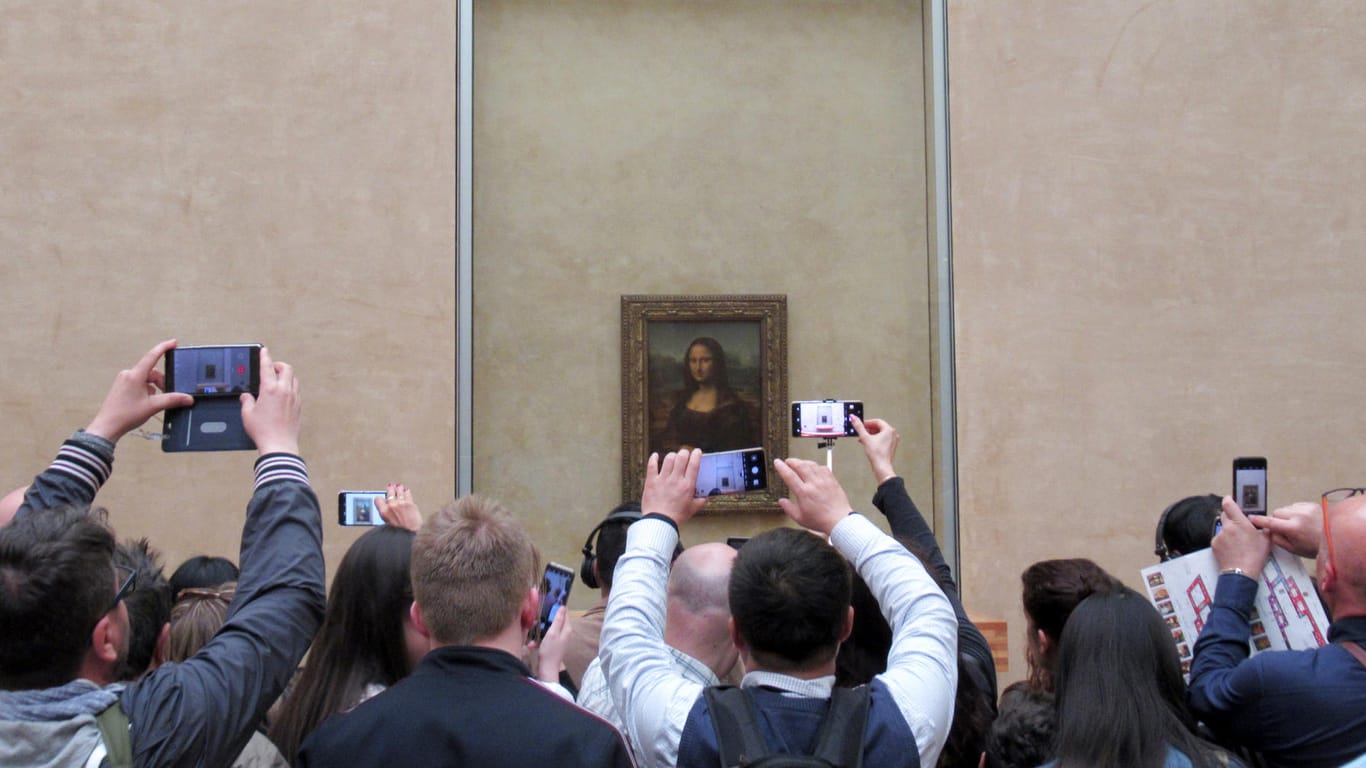 Frankreich, Paris: Besucher stehen mit ihren Handys und Smartphones vor der "Mona Lisa" von Leonardo da Vinci im Louvre. Das weltberühmte Bild, das Leonardo da Vinci vor mehr als 500 Jahren geschaffen hat, lockt alljährlich Millionen von Besuchern an. Es gehört zu den meist besuchten Kunstwerken der Welt – und wird doch kaum betrachtet.