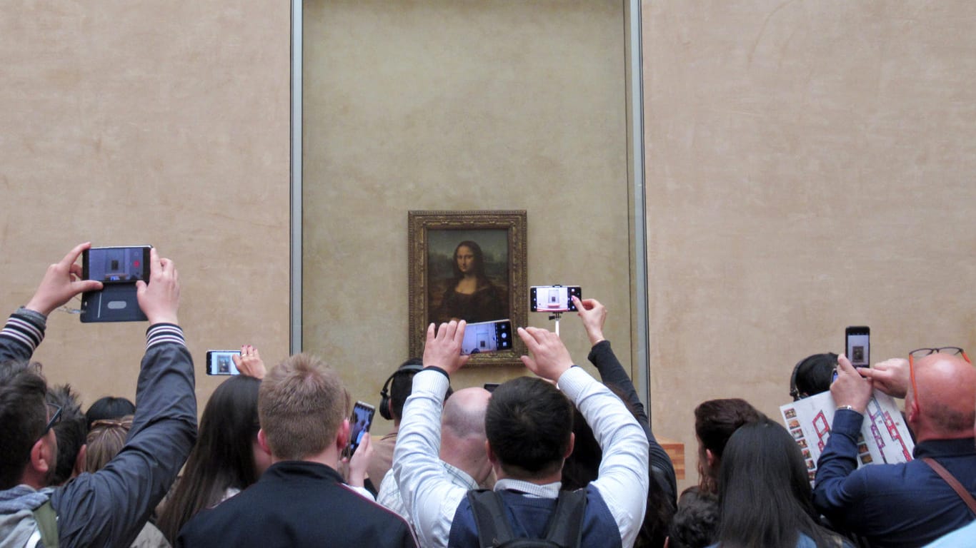 Frankreich, Paris: Besucher stehen mit ihren Handys und Smartphones vor der "Mona Lisa" von Leonardo da Vinci im Louvre. Das weltberühmte Bild, das der Künstler vor mehr als 500 Jahren geschaffen hat, lockt alljährlich Millionen von Besuchern an. Es gehört zu den meist besuchten Kunstwerken der Welt.