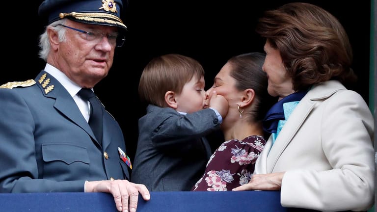 König Carl Gustaf mit Königin Silvia: Im Hintergrund gibt Prinz Oscar seiner Mama Victoria einen Kuss.