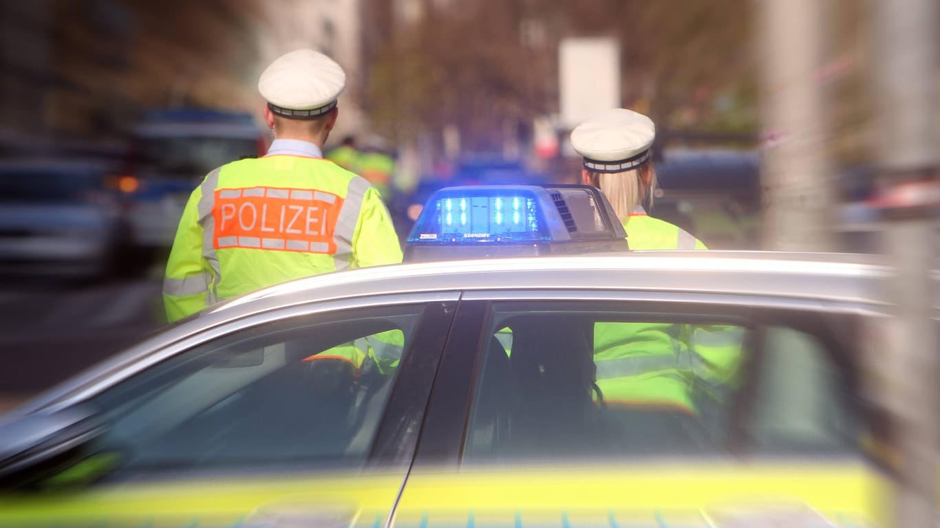 Polizeibeamte vor ihrem Einsatzfahrzeug (Symbolfoto): Die Mutter alarmierte demnach telefonisch die Polizei, als der Sohn gerade den Vater angriff.