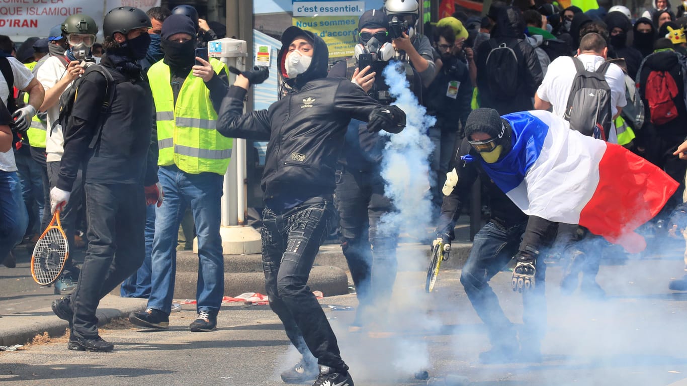 Ein Mann wirft eine Tränengasgranate in Richtung Polizisten: In Paris ist es am Rand einer Gewerkschaftskundgebung zu schweren Krawallen gekommen.