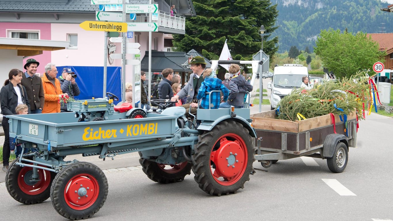 Ein Traktor auf dem Weg zum traditionellen Maibaumaufstellen (Symbolfoto): Ein Fahrzeug mit mehreren Mitfahrern ist in Oberbayern umgekippt – 21 Menschen wurden zum Teil schwer verletzt.