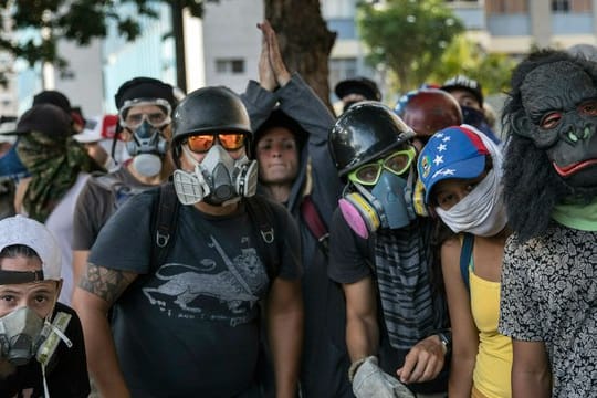 Regierungsgegner beobachten Sicherheitskräfte während Zusammenstößen in Caracas.