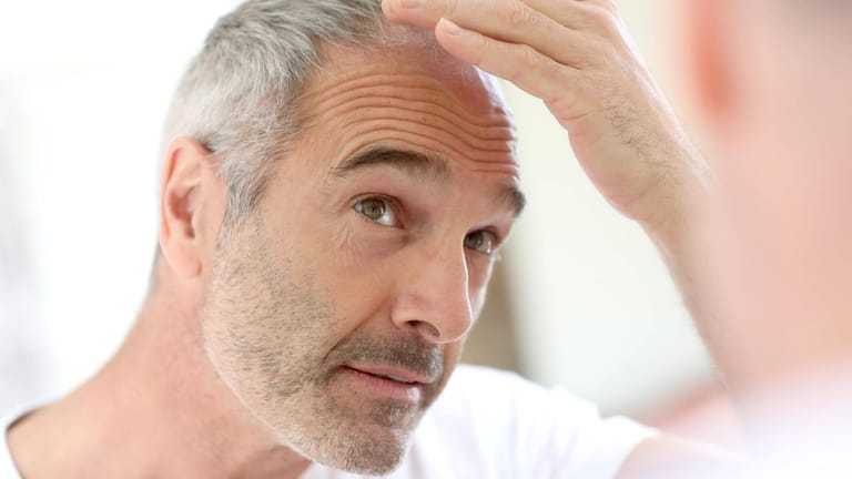 Mann kontrolliert seinen Kopf: Kann Koffein das Wachstum der Haare fördern?