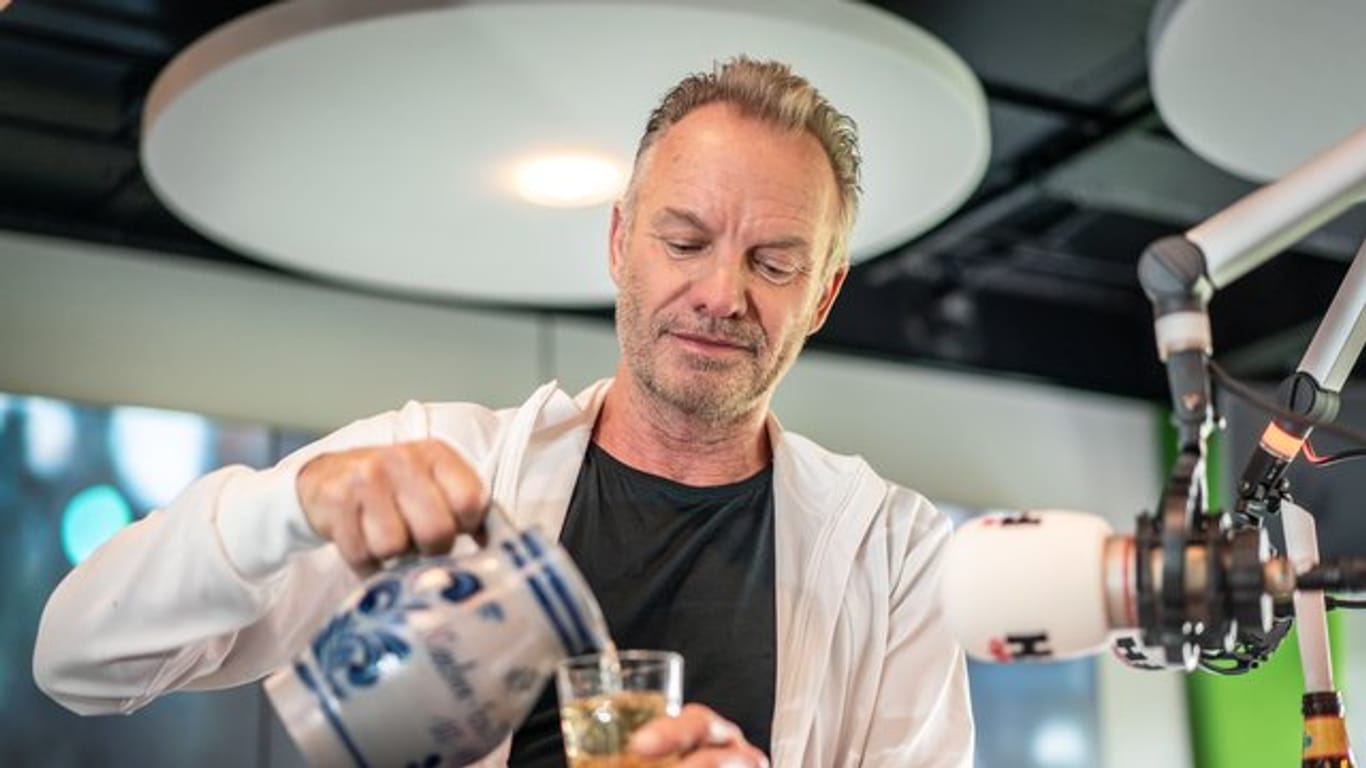 Sting besucht Radio FFH und gießt sich ein Glas hessischen Apfelwein ein.